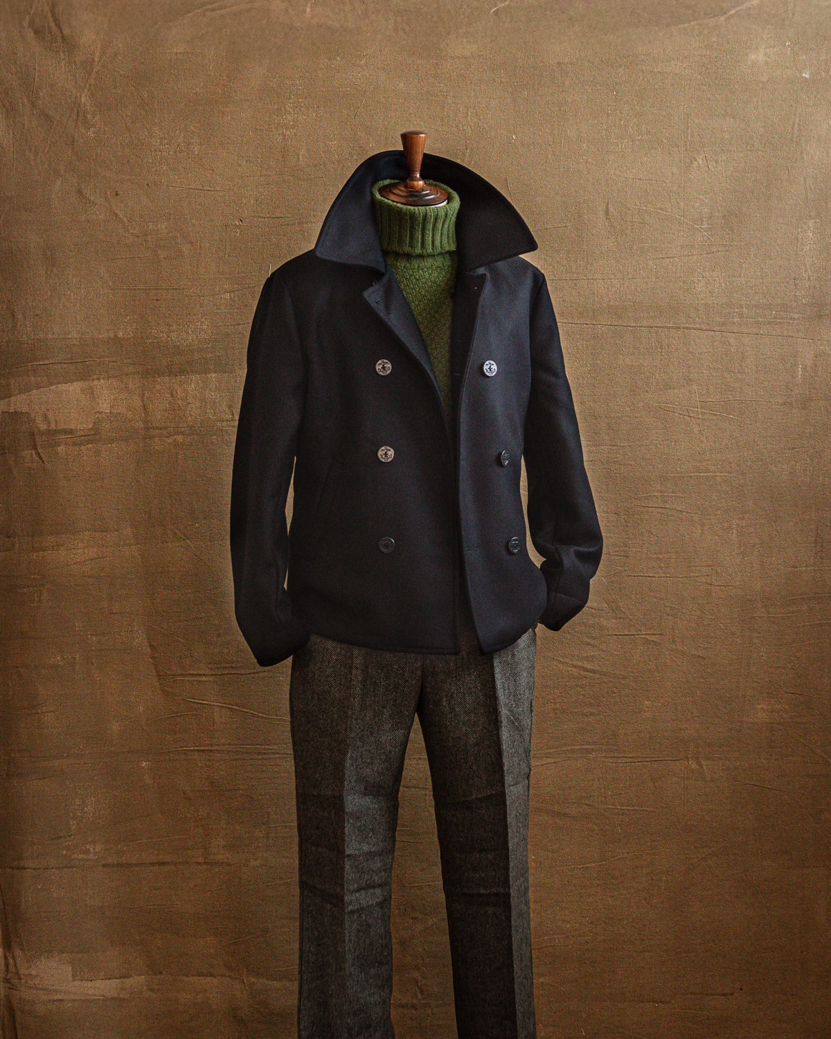 Navy peacoat layered over green knitwear